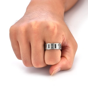 Close-up of men's silver ring with black geometric brick texture on white background
