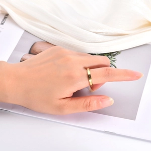 Detail of 3mm gold hammered spinner ring worn on finger over elegant paper backdrop