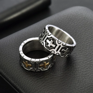 Macro shot of two vintage gothic punk cross rings with embossed floral carvings and wide bands