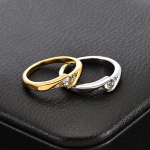 Macro shot of interlocking gold and silver rings with center diamond on black leather