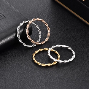 Set of four minimalist 18K gold and silver twisted rope rings on black texture