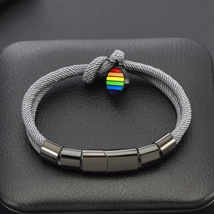 Détail du bracelet en cordon tressé gris avec pendentif en émail arc-en-ciel et métal