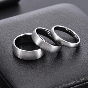 Three-piece set of brushed tungsten steel rings with polished inner bands on black leather