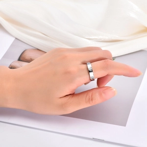 Détail d'une bague argentée avec cristaux ronds et cœurs portée sur fond en satin