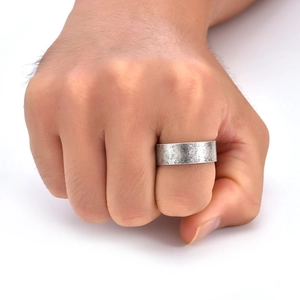 Macro detail of men's wide vintage band ring featuring a matte silver textured finish