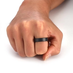 Close-up of minimalist black matte ceramic ring worn on a finger with smooth texture