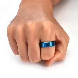 Detail of matte blue brushed titanium steel ring on male finger with white background