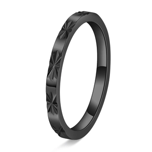 Macro detail of matte black titanium steel ring with minimalist star pattern engraving