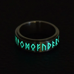 Macro detail of Nordic rune spinner ring with intense green luminous glow on dark steel