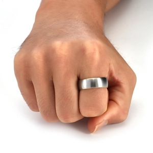 Close-up of a wide brushed tungsten ring for men worn on a hand against white background