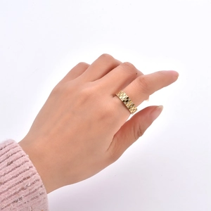 Gros plan d'une bague dorée à motif damier avec zircons portée au doigt d'un mannequin