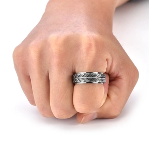 Macro shot of men's vintage silver spinning ring with detailed feather pattern
