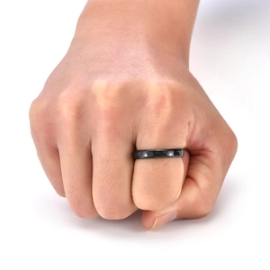 Close-up of matte black tungsten steel ring with textured finish on a finger