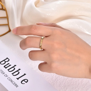 Detail shot of golden irregular gear ring showing textured vertical groove engraving