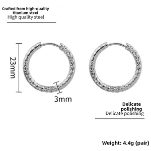 Détail de créoles argentées en acier texturé avec finition martelée et diamètre 23mm