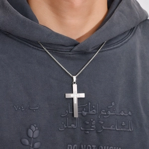 Gros plan d'un pendentif croix en acier titane argenté avec zircons sur une chaîne box