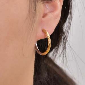 Minimalist gold twisted rope hoop earring with polished finish on model's ear