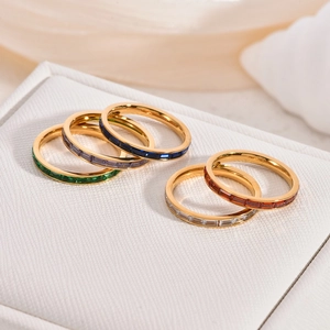 Close-up of five minimalist 18K gold titanium rings set with vibrant colored crystals