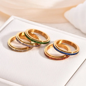 Five pieces of 18K gold spinner rings with colorful zircon inlay on jewelry box