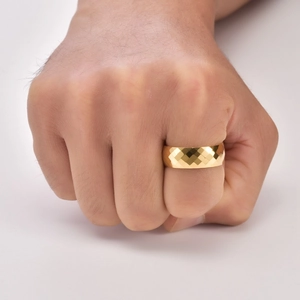 Macro detail of men's golden tungsten ring with textured geometric diamond-cut pattern