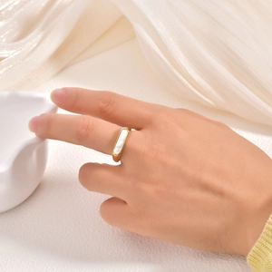 Detailed view of an 18K gold plated ring featuring a white rectangular shell inlay on finger