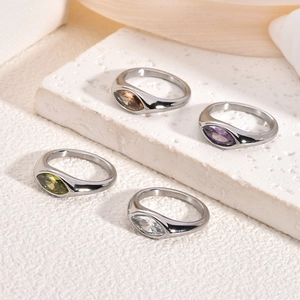 Detailed view of four colorful marquise-cut zircon rings on a textured stone surface