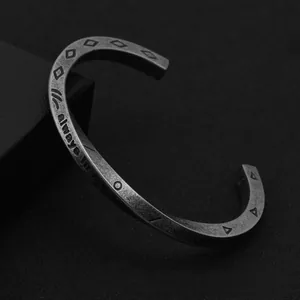 Detailed close-up of a vintage titanium steel cuff bracelet with engraved geometric patterns