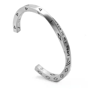 Detailed close-up of engraved Always in my heart quote on a matte steel open bangle