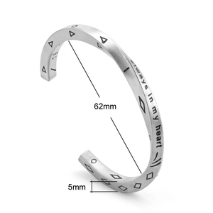 Macro view of silver titanium steel cuff bangle with 'always in my heart' engraving