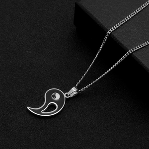 Gros plan du pendentif Yin Yang avec chaîne gourmette argentée sur fond noir