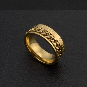 Détail macro d'une bague rotative homme en acier doré avec runes et chaîne cubaine