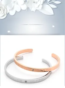 Detailed view of C-shaped titanium steel bracelet with engraved text and small zircon