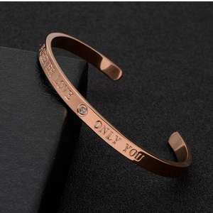 Detail of rose gold C-shaped bangle with Forever Love engraving and small zircon stone
