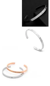 Detail of C-shaped stainless steel bracelets with Forever Love engraving and small crystal
