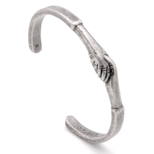 Macro detail of silver cuff bracelet with handshake engraving and matte finish