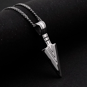 Macro shot of mirror-polished arrowhead pendant with engraved V-lines and metal chain