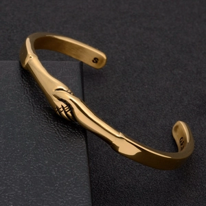 Golden titanium steel C-shaped cuff bracelet featuring a detailed handshake design