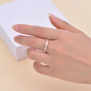 Primo piano dettagliato di un anello sottile in oro rosa opaco con trama luccicante al dito