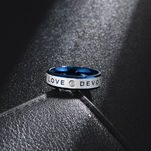 Dettaglio macro di anello in acciaio spazzolato, interno blu, testo LOVE DEVOTION e cristallo