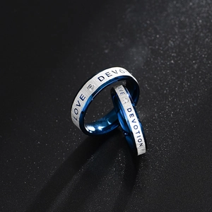 Dettaglio di anelli di coppia blu e argento con incisione LOVE e DEVOTION e zircone