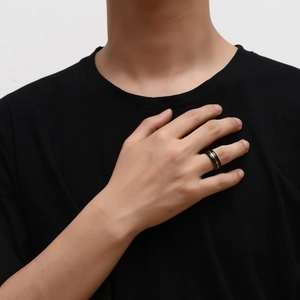 Close-up of men's matte black stainless steel ring with a gold textured center inlay