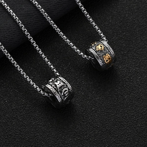 Macro detail of retro stainless steel cylinder pendants with engraved religious symbols
