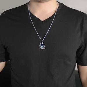 Close-up of a silver crescent moon necklace with a luminous blue galaxy orb on a model