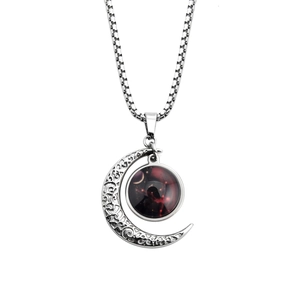 Macro shot of silver crescent moon pendant with red nebula ball on box chain