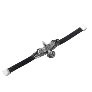 Détail du motif d'aigle argenté sur un bracelet en cuir tressé noir avec aspect carbone