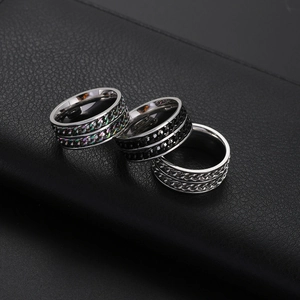 Three men's rotatable cuban chain rings in rainbow, black, and silver on leather