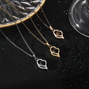 Trois colliers de projection cœur en argent, or et or rose sur fond de sable noir