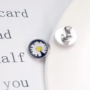 Gros plan de boucles d'oreilles marguerite montrant le motif floral et le fermoir papillon