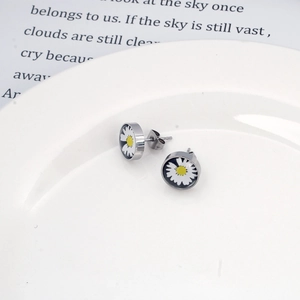 Détails macro des boucles d'oreilles marguerite en émail noir avec base en acier poli