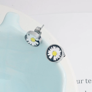 Gros plan sur des boucles d'oreilles marguerites en acier sur un bol en céramique